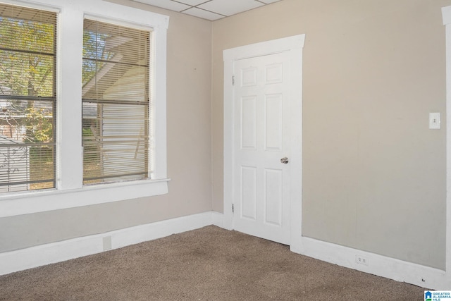 empty room with a paneled ceiling and carpet floors