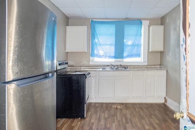 kitchen with a drop ceiling, stainless steel appliances, dark wood-type flooring, sink, and white cabinets