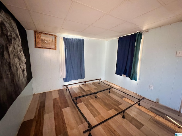 interior space featuring a drop ceiling and wood-type flooring