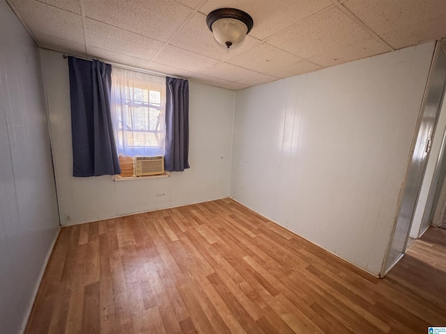 unfurnished room with a paneled ceiling, hardwood / wood-style flooring, and cooling unit