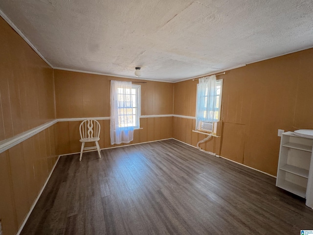 empty room with dark hardwood / wood-style floors, wood walls, and a textured ceiling