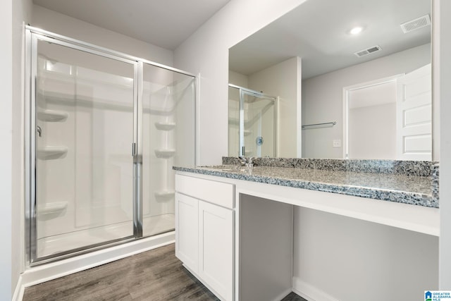 bathroom featuring hardwood / wood-style floors, a shower with door, and vanity