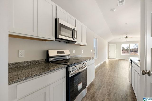 kitchen with ceiling fan, vaulted ceiling, dark stone countertops, white cabinetry, and appliances with stainless steel finishes