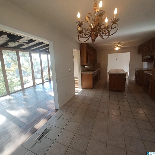 kitchen featuring ceiling fan with notable chandelier, a kitchen island, and light tile patterned flooring