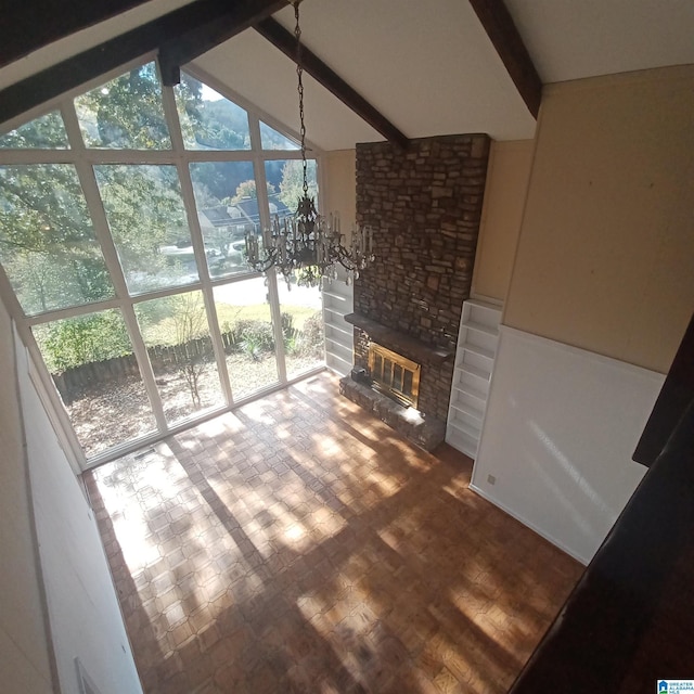 living room featuring vaulted ceiling with beams, a stone fireplace, wood-type flooring, and an inviting chandelier