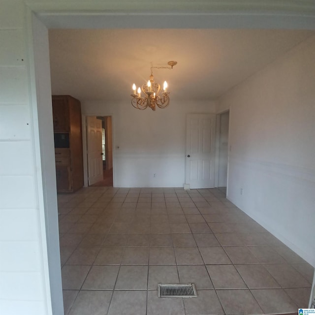 spare room with light tile patterned floors and a chandelier