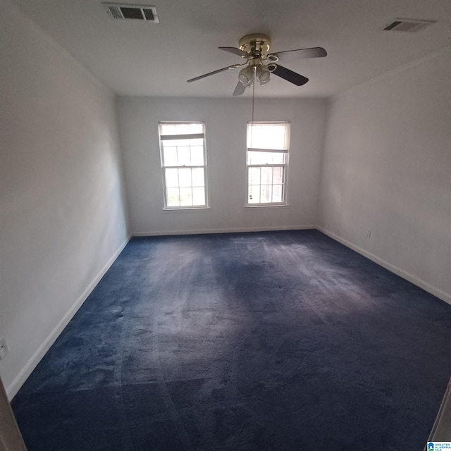 unfurnished room with dark colored carpet and ceiling fan