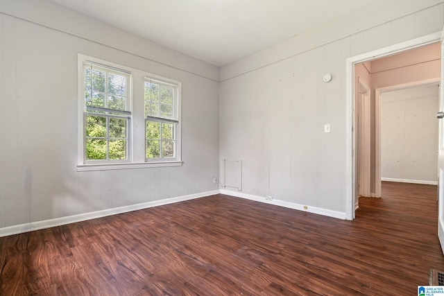 spare room featuring wood walls and dark hardwood / wood-style flooring