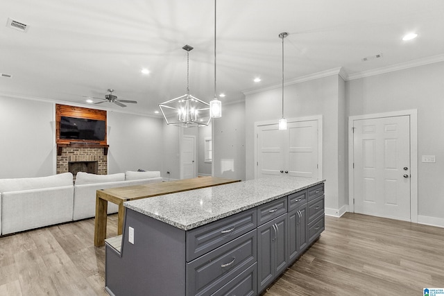 kitchen featuring crown molding, light wood finished floors, gray cabinets, visible vents, and a brick fireplace