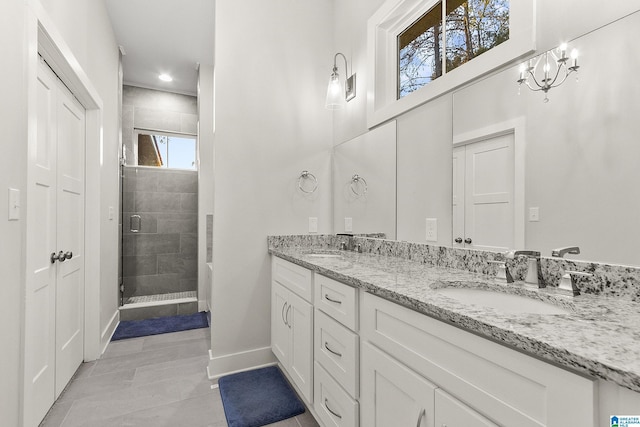 bathroom with a sink, a shower stall, baseboards, and double vanity