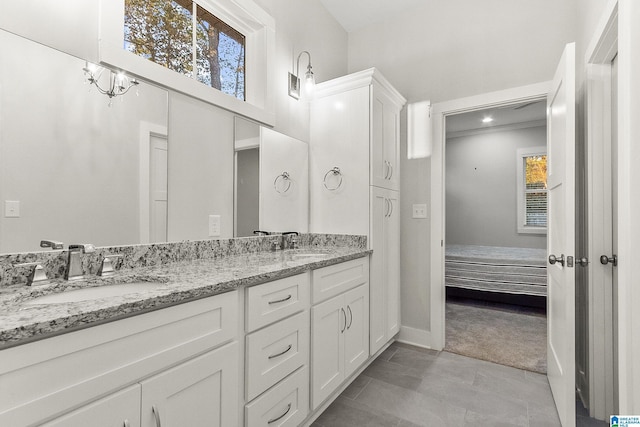 full bath with double vanity, ensuite bath, a sink, and baseboards