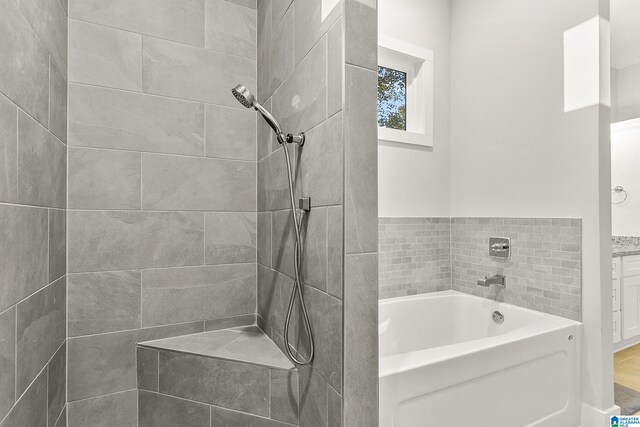 bathroom with a tile shower and a bath