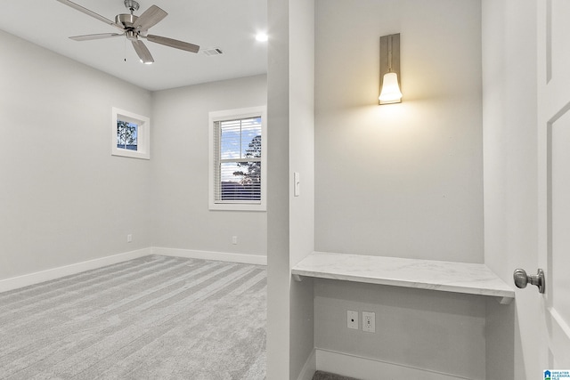 carpeted empty room featuring a ceiling fan, visible vents, and baseboards