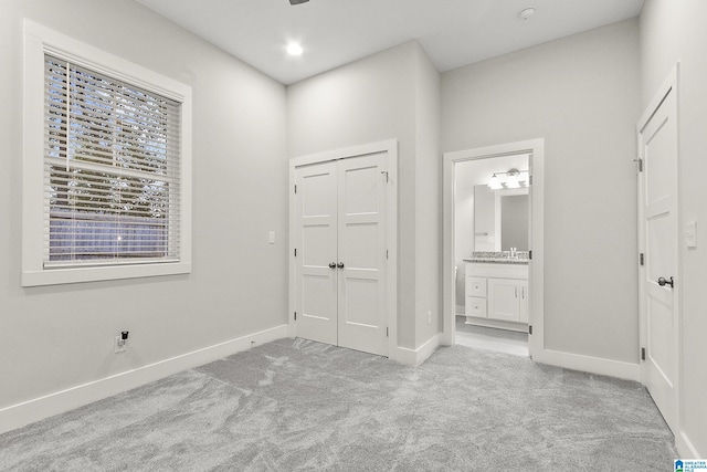 unfurnished bedroom featuring baseboards, ensuite bathroom, carpet flooring, a closet, and recessed lighting