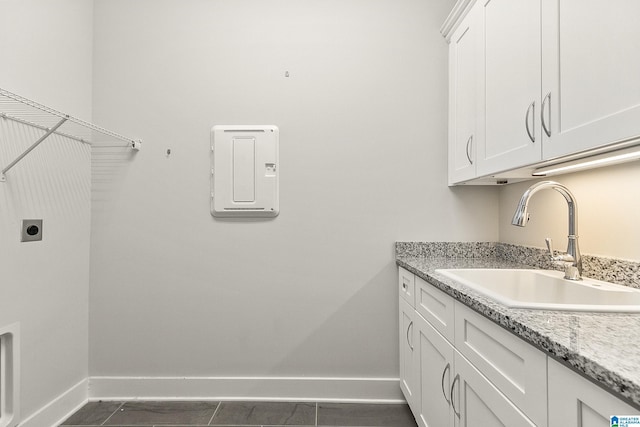 clothes washing area with cabinet space, a sink, electric dryer hookup, and baseboards