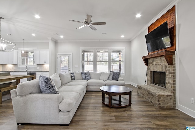 living area with baseboards, dark wood-type flooring, crown molding, a fireplace, and recessed lighting