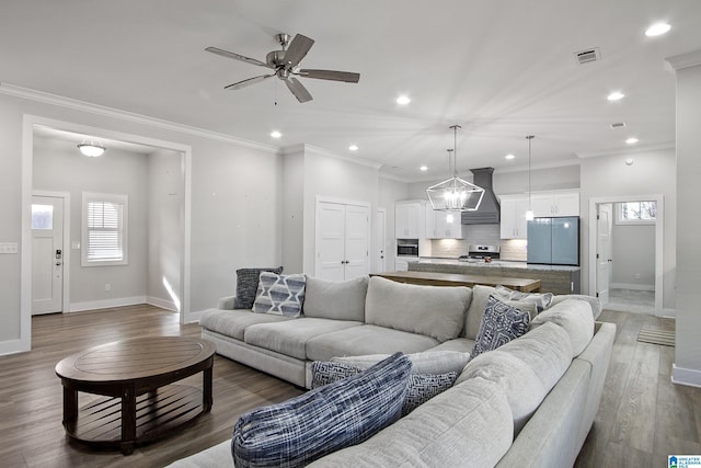 living area featuring baseboards, visible vents, crown molding, and wood finished floors