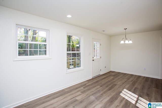 unfurnished room featuring a chandelier and wood-type flooring