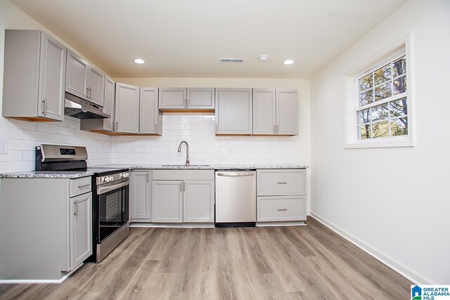 kitchen featuring light stone countertops, sink, light hardwood / wood-style floors, gray cabinets, and appliances with stainless steel finishes