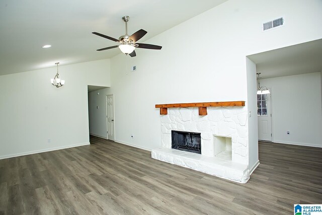 unfurnished living room featuring high vaulted ceiling, dark hardwood / wood-style floors, a stone fireplace, and ceiling fan