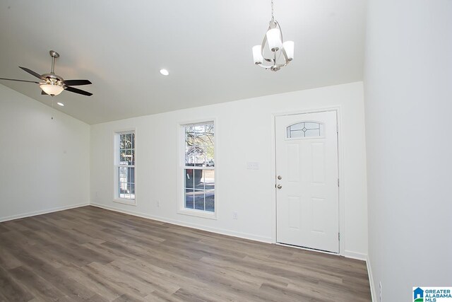 foyer with hardwood / wood-style floors, ceiling fan with notable chandelier, and vaulted ceiling