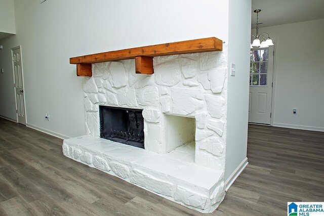 interior details with a stone fireplace, wood-type flooring, and an inviting chandelier