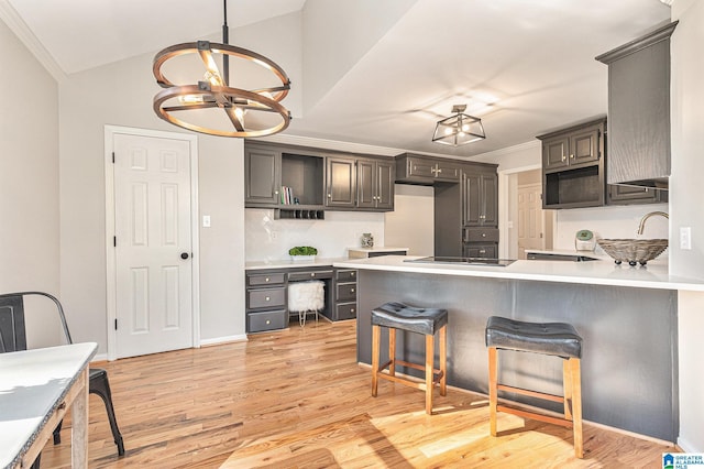 kitchen with a breakfast bar, an inviting chandelier, crown molding, light hardwood / wood-style flooring, and kitchen peninsula