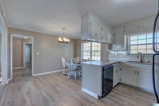 kitchen with kitchen peninsula, sink, dishwasher, white cabinetry, and plenty of natural light