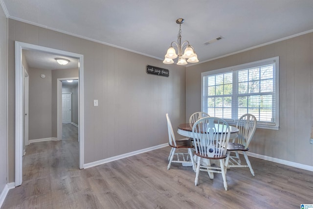 dining room with an inviting chandelier, light hardwood / wood-style flooring, and ornamental molding