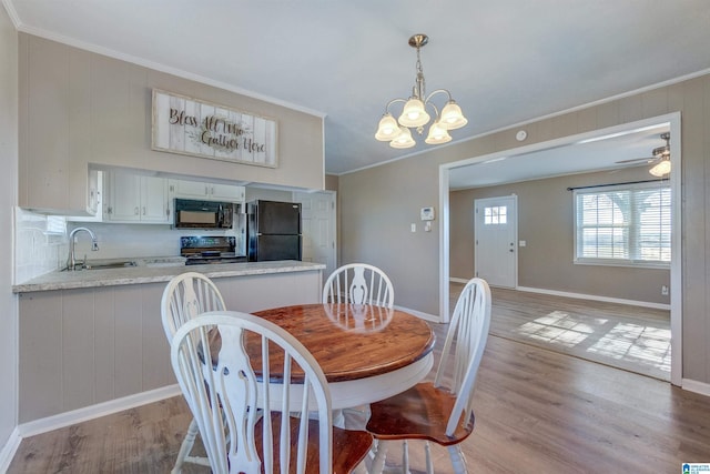 dining space with ceiling fan with notable chandelier, light hardwood / wood-style flooring, crown molding, and sink