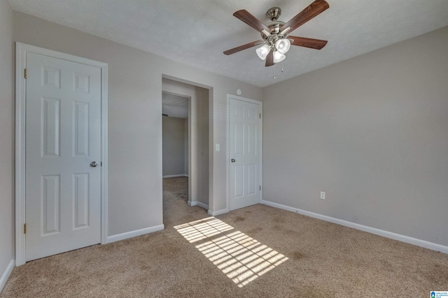 unfurnished bedroom featuring ceiling fan, light colored carpet, and a textured ceiling