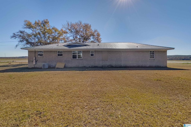 rear view of house with central AC and a lawn