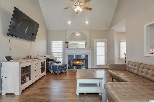 living room with ceiling fan, a premium fireplace, dark wood-type flooring, and high vaulted ceiling