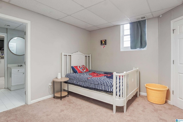 carpeted bedroom featuring ensuite bathroom, a drop ceiling, and sink