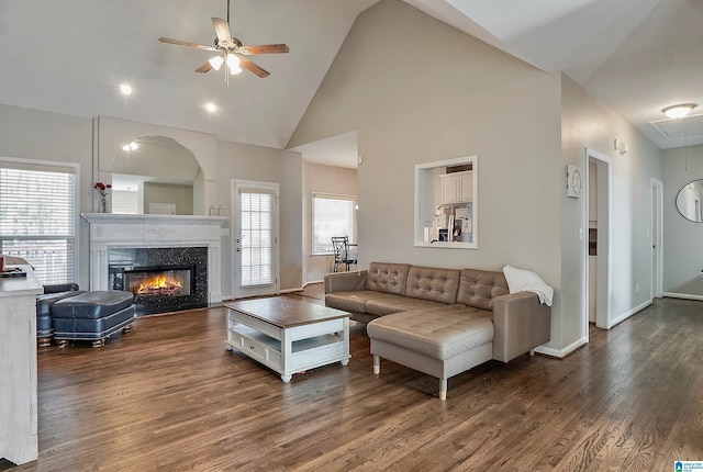 living room featuring a high end fireplace, ceiling fan, high vaulted ceiling, and dark wood-type flooring