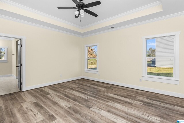 unfurnished room with hardwood / wood-style floors, ceiling fan, crown molding, and a tray ceiling