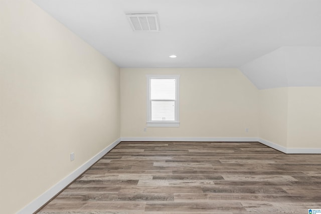 additional living space featuring wood-type flooring and vaulted ceiling