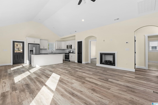 unfurnished living room featuring ceiling fan, sink, high vaulted ceiling, and light wood-type flooring