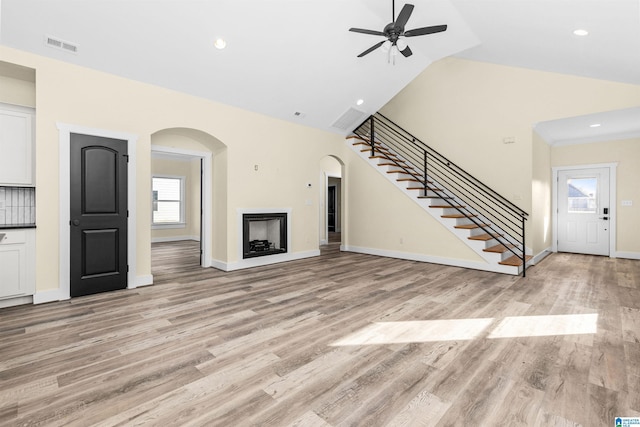 unfurnished living room with ceiling fan, high vaulted ceiling, and light hardwood / wood-style flooring