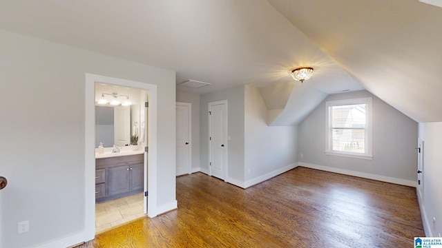 additional living space with hardwood / wood-style flooring and vaulted ceiling