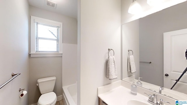 bathroom with vanity, a bath, and toilet