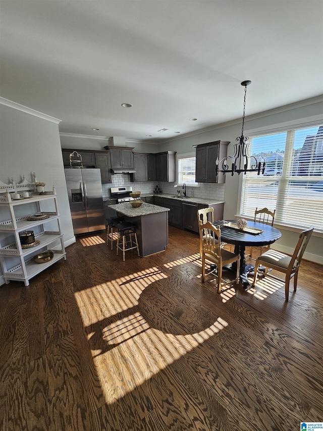 dining area featuring dark hardwood / wood-style floors, ornamental molding, sink, and an inviting chandelier