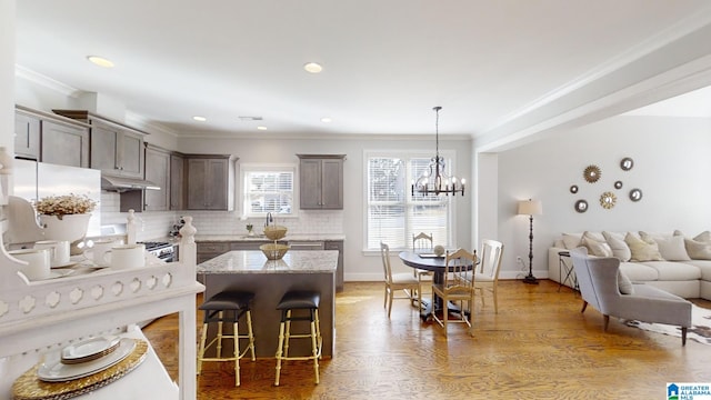 kitchen with tasteful backsplash, crown molding, a center island, and hanging light fixtures