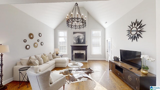 living room featuring an inviting chandelier, hardwood / wood-style flooring, and vaulted ceiling