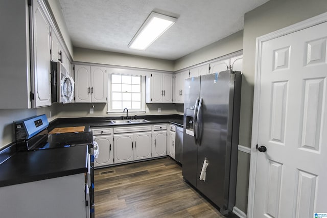 kitchen with a textured ceiling, sink, stainless steel appliances, and dark wood-type flooring