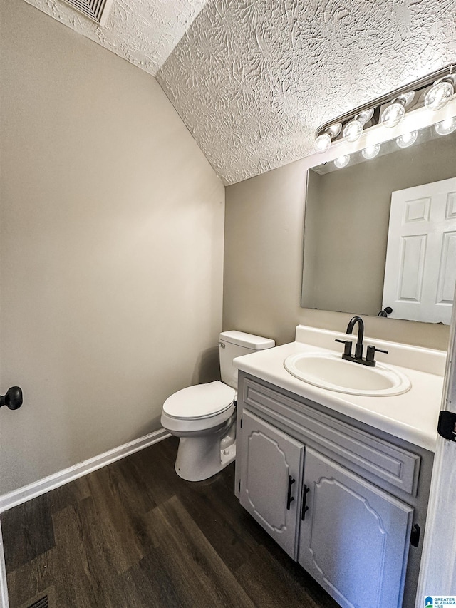 bathroom featuring vanity, a textured ceiling, hardwood / wood-style floors, toilet, and lofted ceiling