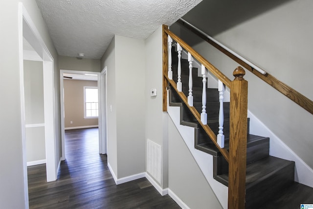 stairway with wood-type flooring and a textured ceiling