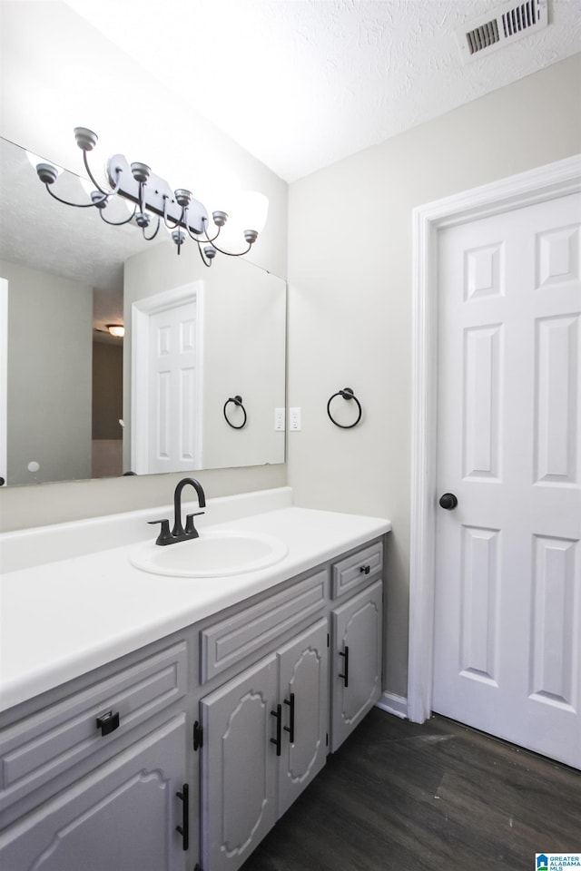 bathroom with a textured ceiling, vanity, hardwood / wood-style flooring, and a notable chandelier