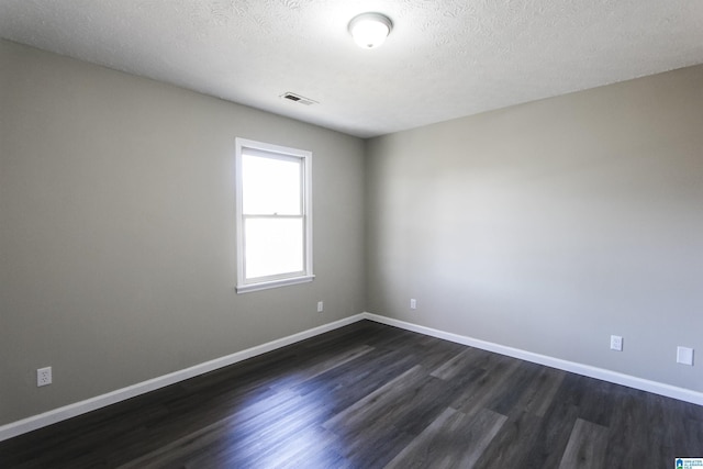 empty room with a textured ceiling and dark wood-type flooring