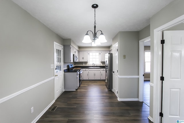 kitchen with dark hardwood / wood-style floors, sink, appliances with stainless steel finishes, and a chandelier